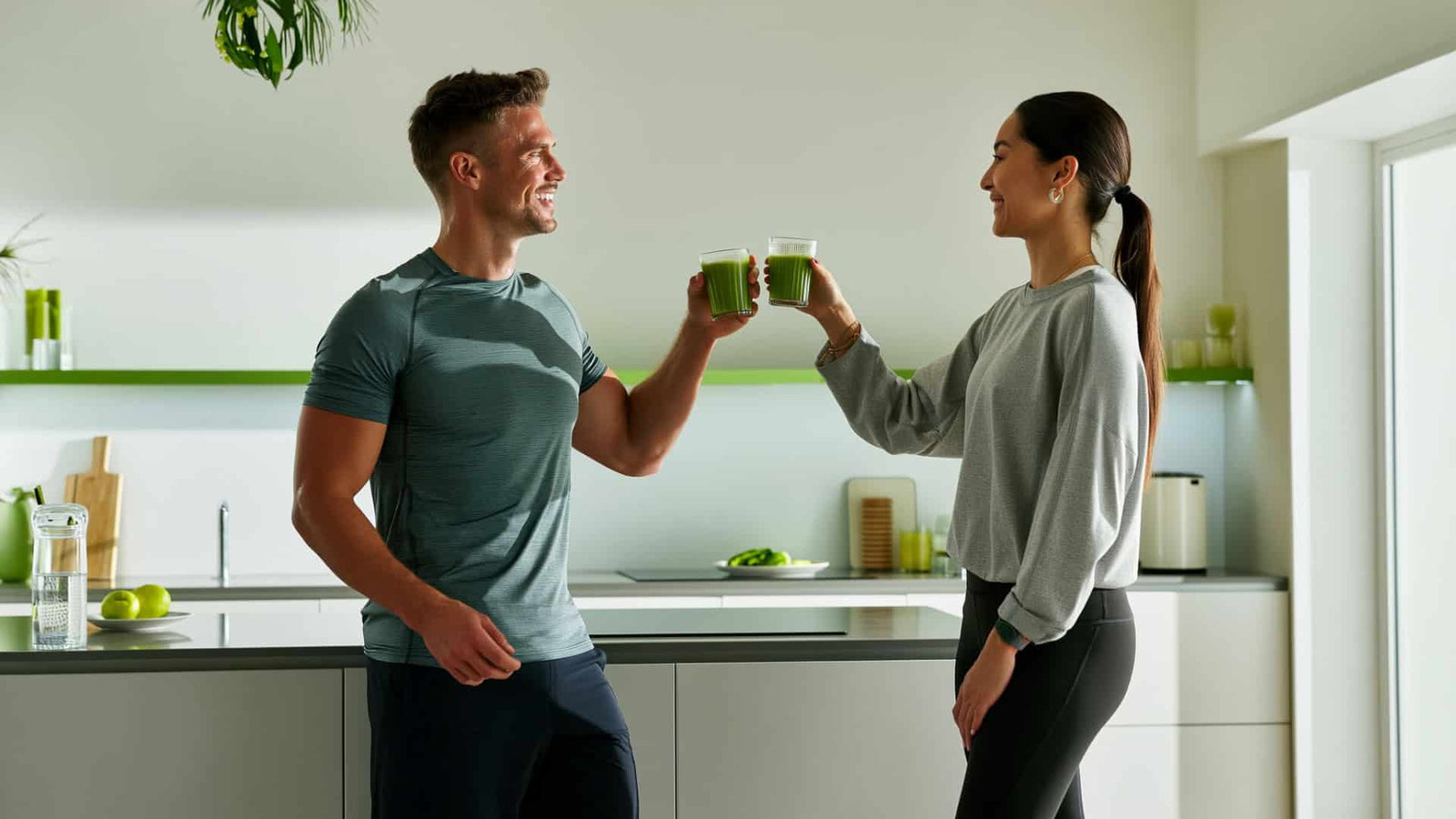 personal trainer in gym gear is handing a glass of green drink to a client