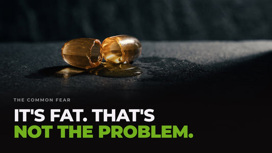 A split omega-3 capsule with golden oil welling out onto dark slate, captioned “It's fat. That's not the problem.”
