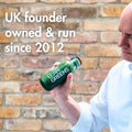 Person holding a green 'Lean Greens' bottle with text about UK ownership and founding year.