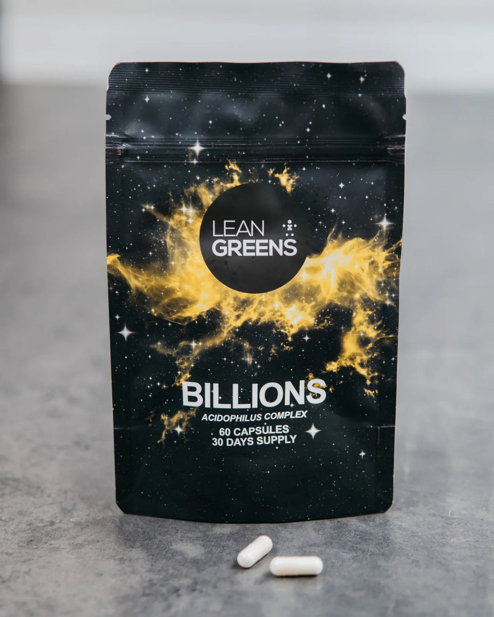 A pouch of Lean Greens Billions standing on a kitchen worktop, with two capsules lying in front of it